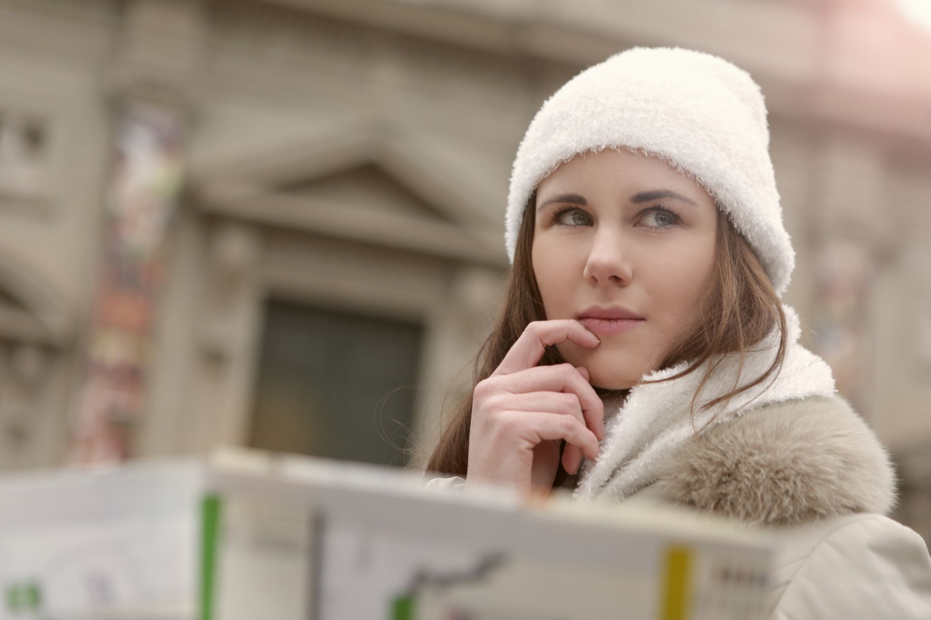 young lady in warm wear thinking in city street